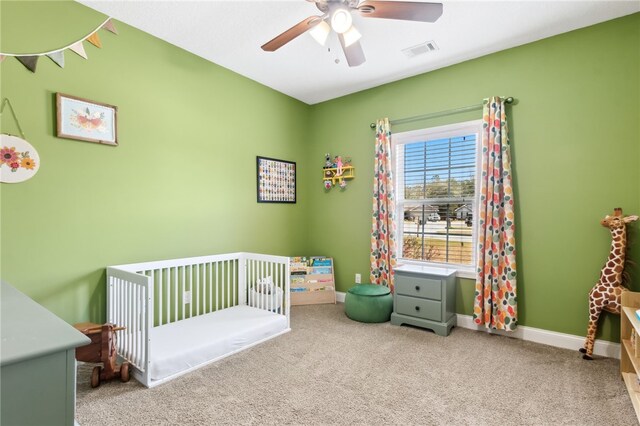 bedroom with ceiling fan, visible vents, baseboards, a nursery area, and carpet