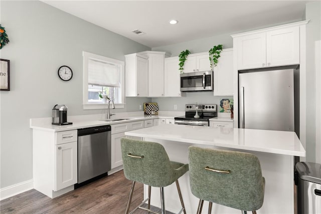 1616 Ashantilly Dr, Darien, GA 31305 - kitchen with stainless steel appliances, dark wood-style floors, a breakfast bar area, white cabinets, and recessed lighting