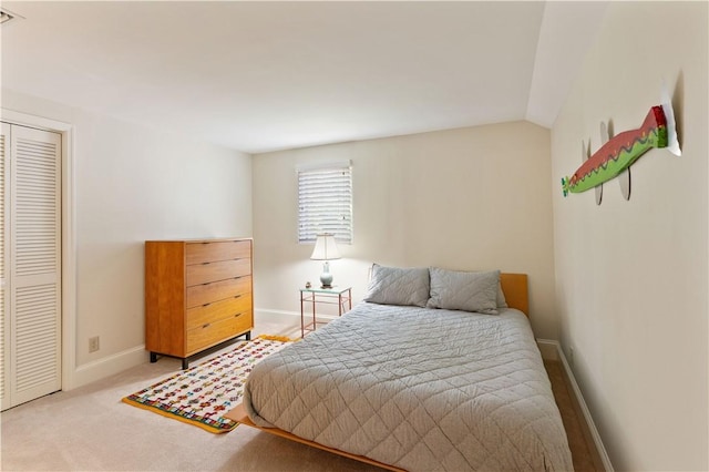 carpeted bedroom featuring vaulted ceiling, a closet, and baseboards