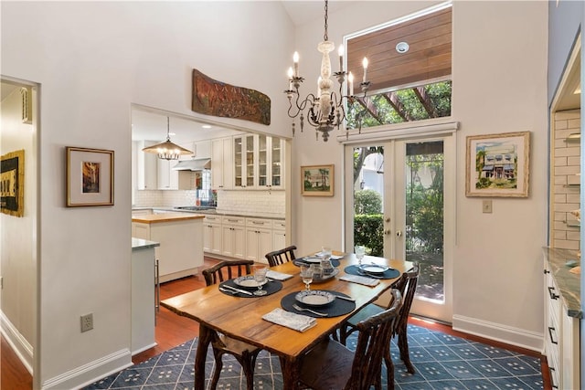 dining room featuring a chandelier, dark wood-style flooring, a towering ceiling, baseboards, and french doors