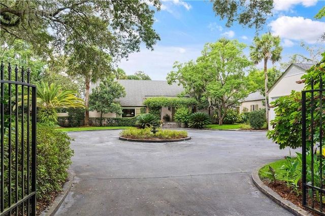 view of front of home featuring fence, curved driveway, and stucco siding