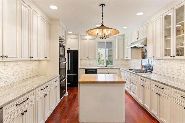 kitchen with under cabinet range hood, dark wood-style flooring, a kitchen island, wood counters, and black appliances