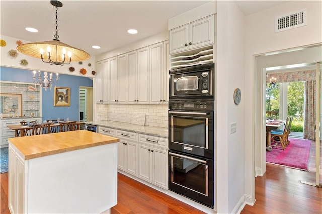 kitchen featuring dark wood-type flooring, wood counters, visible vents, and a notable chandelier