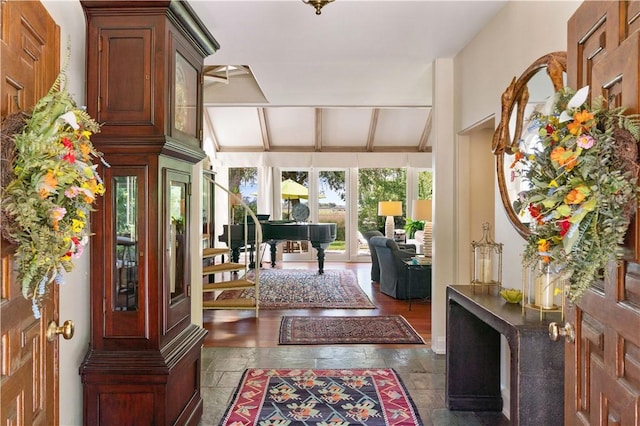 foyer with lofted ceiling with beams, stairway, and stone tile flooring