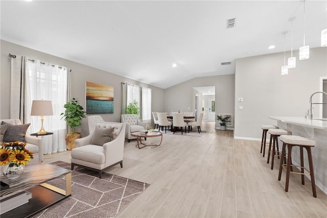 living room featuring light wood-type flooring, lofted ceiling, and sink