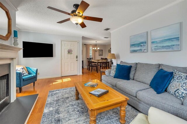103 Travellers Way, Saint Simons Island, GA 31522 - living room with a chandelier, a fireplace, crown molding, a ceiling fan, and wood finished floors