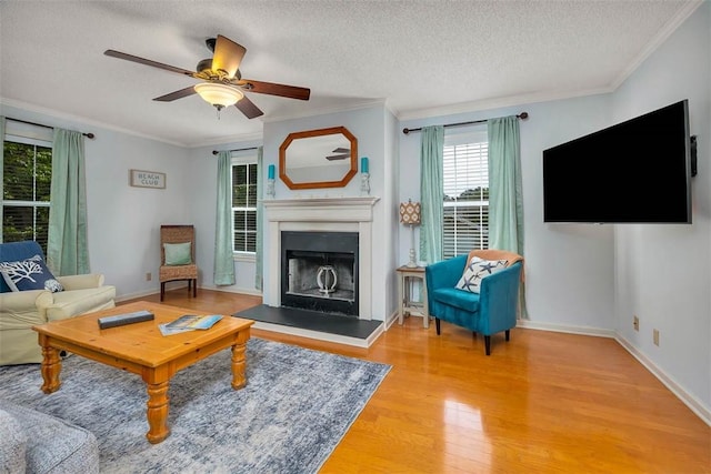 103 Travellers Way, Saint Simons Island, GA 31522 - living room featuring wood finished floors, a fireplace with raised hearth, a textured ceiling, crown molding, and a ceiling fan