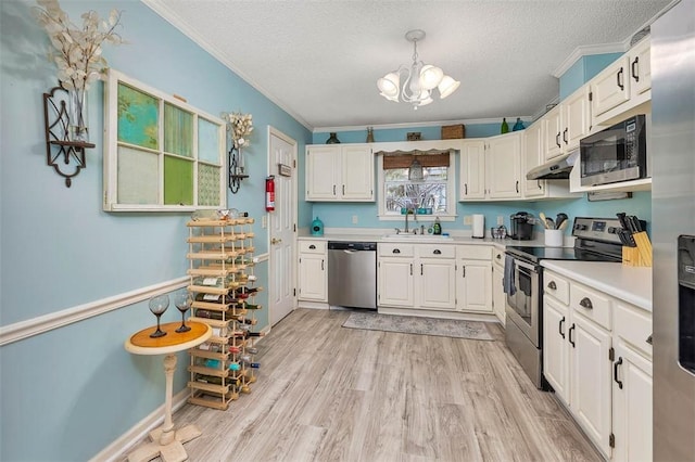103 Travellers Way, Saint Simons Island, GA 31522 - kitchen featuring stainless steel appliances, under cabinet range hood, light countertops, a textured ceiling, and a chandelier
