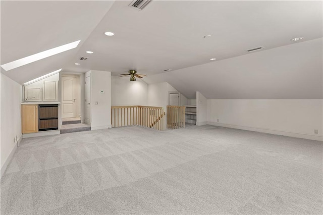 bonus room featuring light colored carpet, lofted ceiling with skylight, and ceiling fan