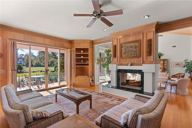 living room featuring a multi sided fireplace, light wood-type flooring, vaulted ceiling, and ceiling fan