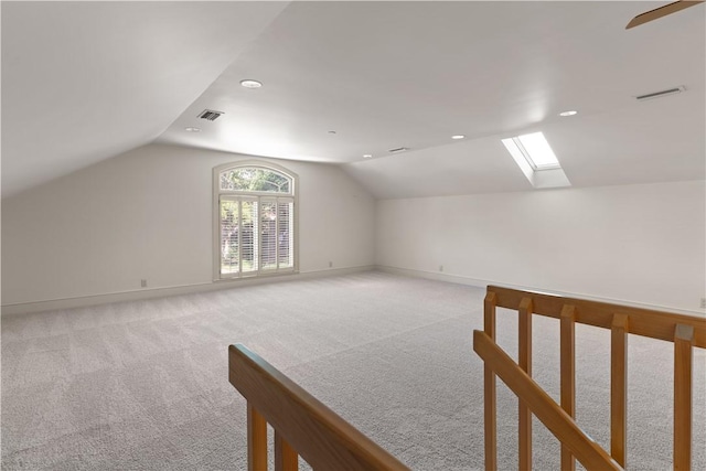 bonus room featuring ceiling fan, light colored carpet, and lofted ceiling with skylight