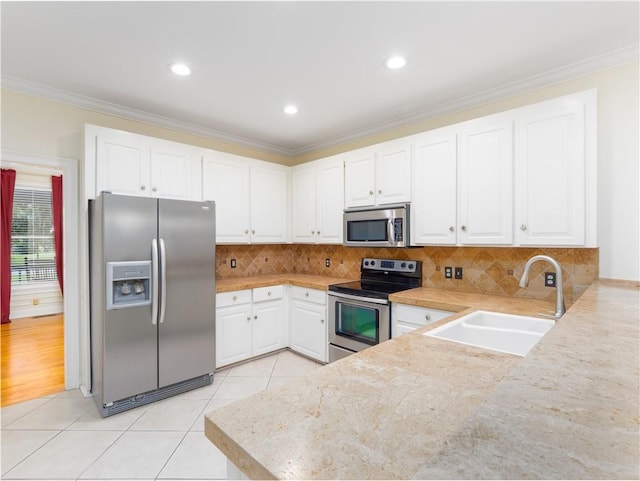 kitchen with appliances with stainless steel finishes, white cabinetry, crown molding, and sink