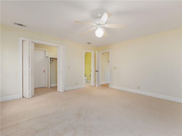 unfurnished bedroom featuring ceiling fan, ensuite bathroom, and light carpet