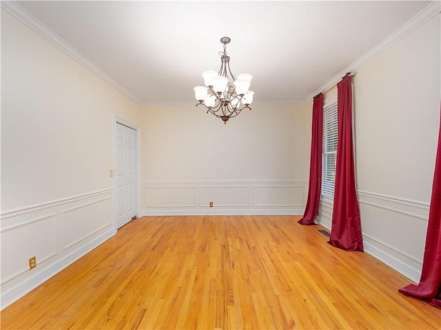 spare room featuring crown molding, wood-type flooring, and a notable chandelier