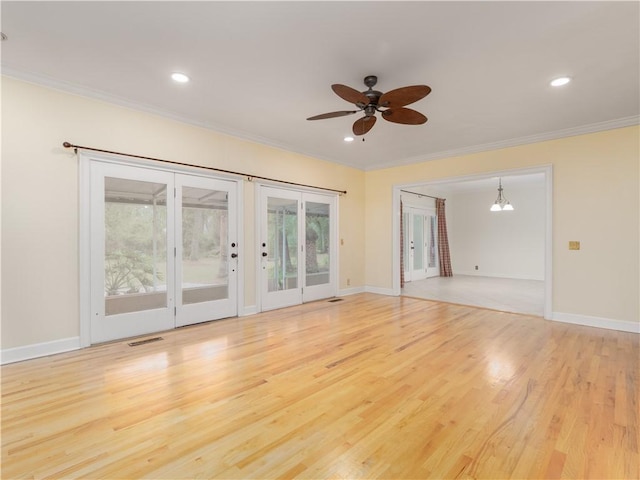 spare room with ceiling fan with notable chandelier, light wood-type flooring, and crown molding