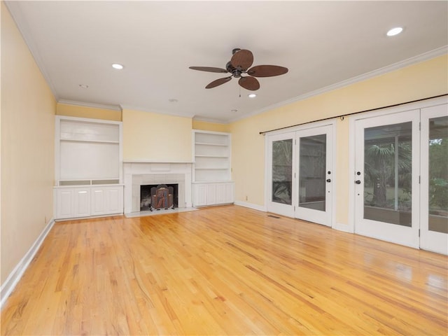 unfurnished living room featuring french doors, light hardwood / wood-style flooring, ceiling fan, ornamental molding, and a tiled fireplace