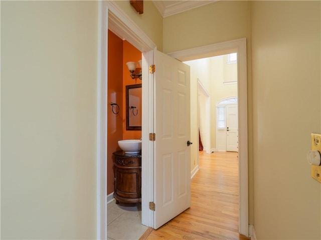 corridor with light wood-type flooring and ornamental molding