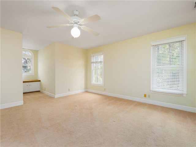 spare room featuring light carpet, plenty of natural light, and ceiling fan