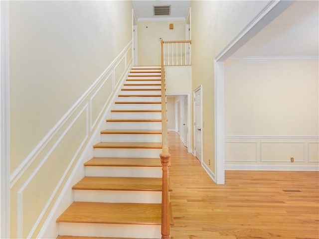 staircase with hardwood / wood-style floors and ornamental molding