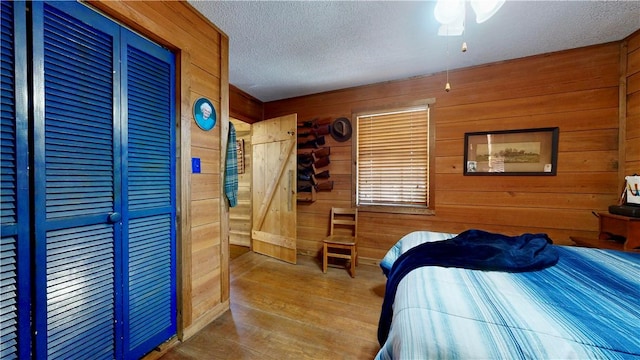 bedroom featuring wood-type flooring, ceiling fan, a textured ceiling, and wood walls