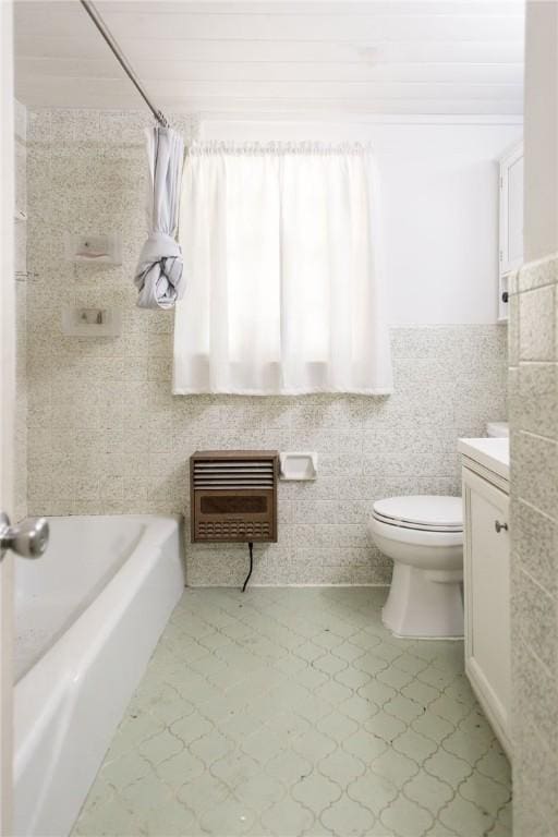 bathroom with tile patterned flooring, heating unit, toilet, vanity, and tile walls