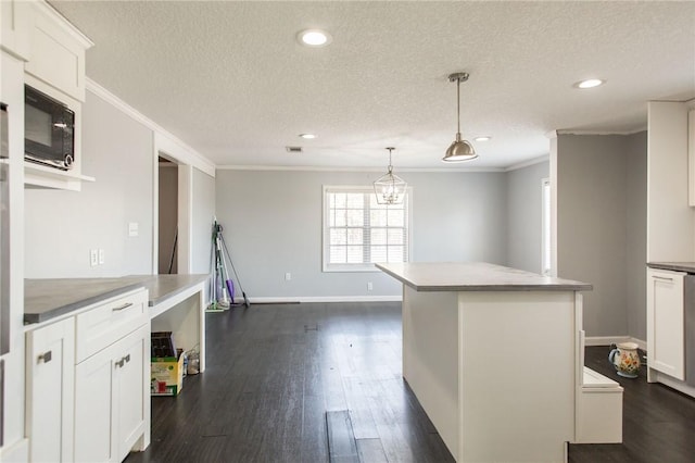 kitchen with a kitchen island, black microwave, a textured ceiling, and crown molding