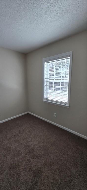 empty room featuring a textured ceiling and dark colored carpet