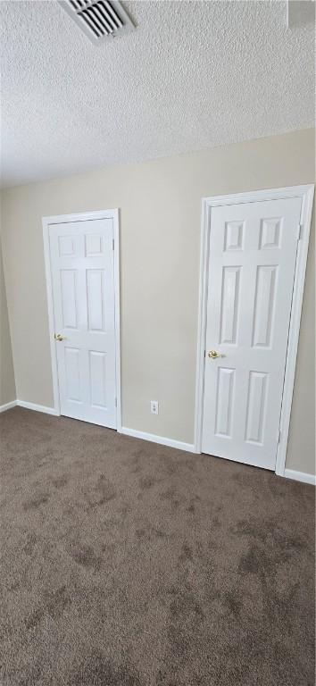 carpeted empty room featuring a textured ceiling