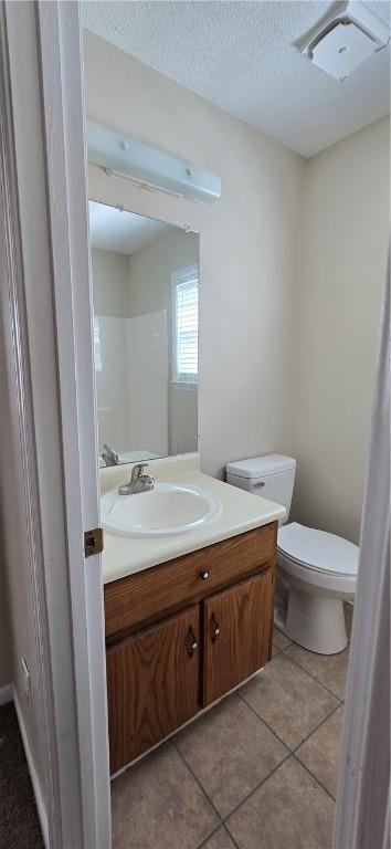 bathroom featuring tile patterned floors, vanity, toilet, and a textured ceiling