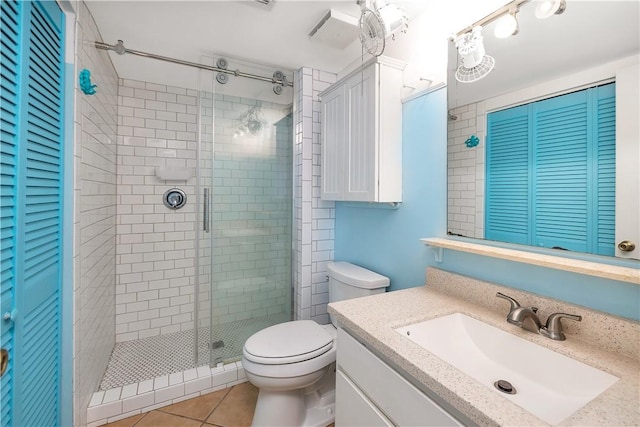 bathroom featuring tile patterned flooring, vanity, toilet, and a shower with shower door