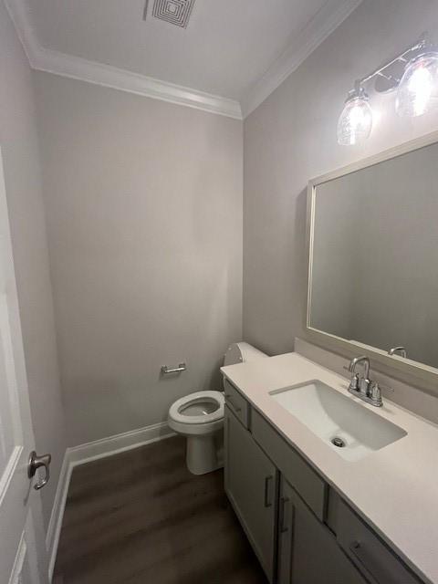 bathroom with hardwood / wood-style floors, vanity, toilet, and crown molding