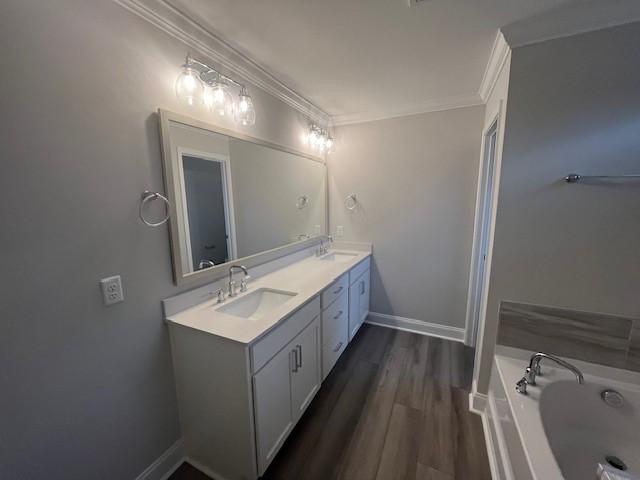 bathroom featuring a tub to relax in, hardwood / wood-style flooring, vanity, and ornamental molding