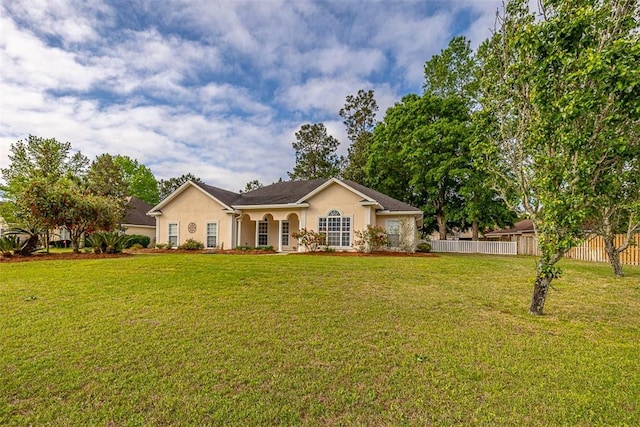 ranch-style home featuring stucco siding, fence, and a front lawn