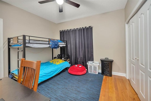 bedroom with a closet, baseboards, a ceiling fan, and wood finished floors