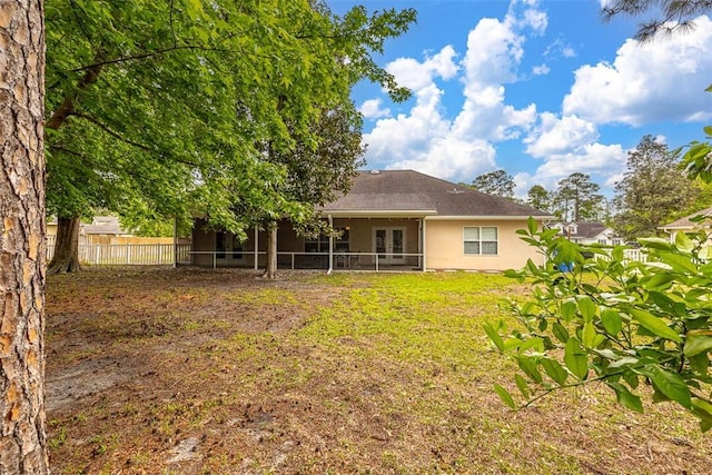 back of property with fence, a sunroom, and stucco siding