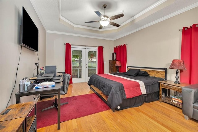 bedroom with access to outside, ornamental molding, french doors, a raised ceiling, and wood finished floors