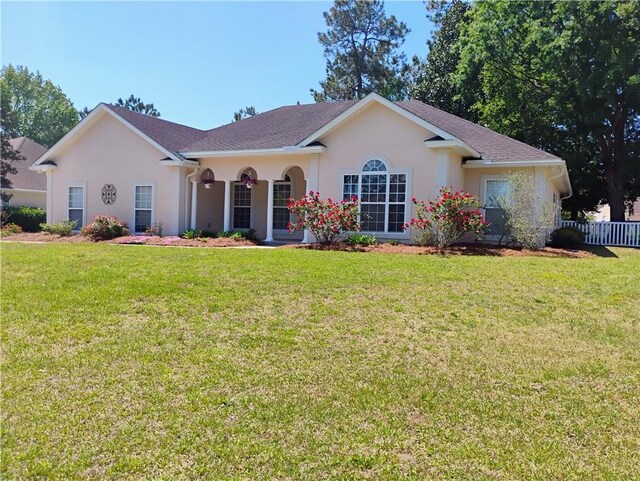 ranch-style home featuring stucco siding, fence, and a front lawn