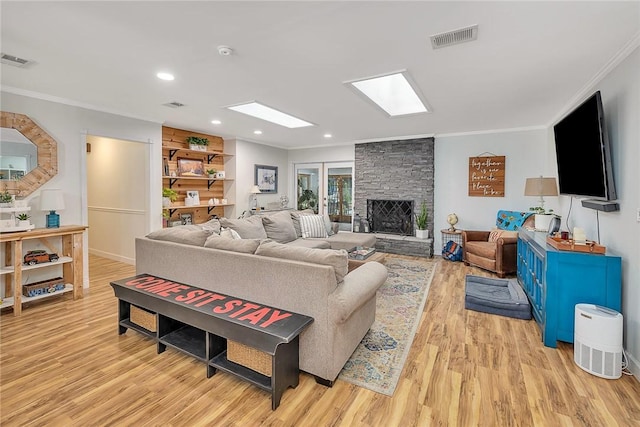 living room featuring a stone fireplace, french doors, light hardwood / wood-style floors, and ornamental molding