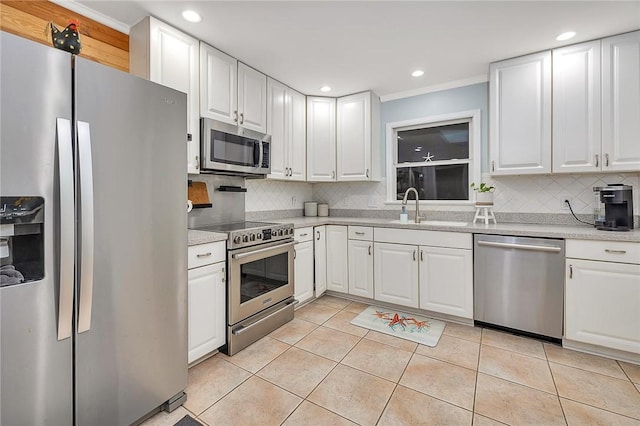 kitchen featuring decorative backsplash, appliances with stainless steel finishes, sink, light tile patterned floors, and white cabinets