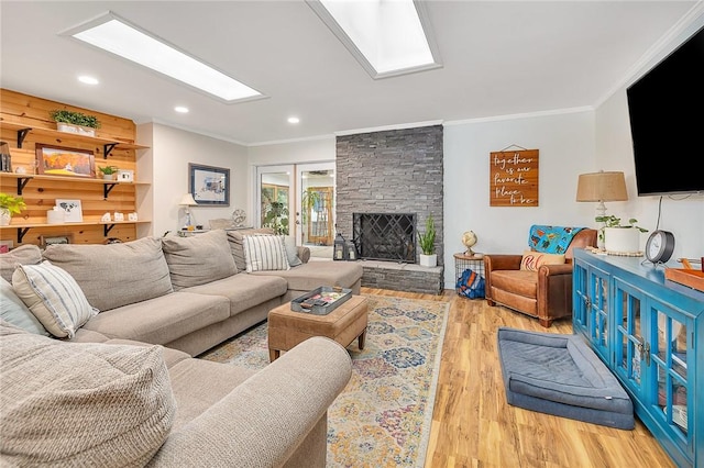 living room with a stone fireplace, light wood-type flooring, and crown molding