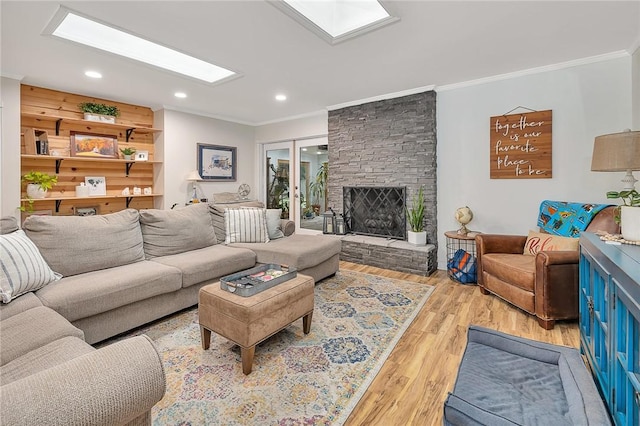 living room with light wood-type flooring, a stone fireplace, and crown molding