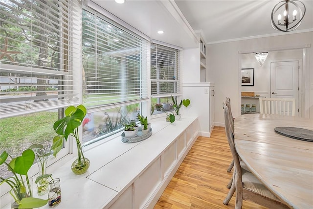 dining area featuring crown molding, light hardwood / wood-style flooring, and a notable chandelier