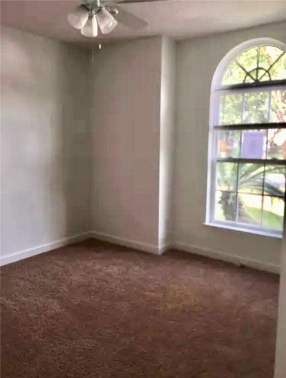 spare room featuring dark carpet and ceiling fan