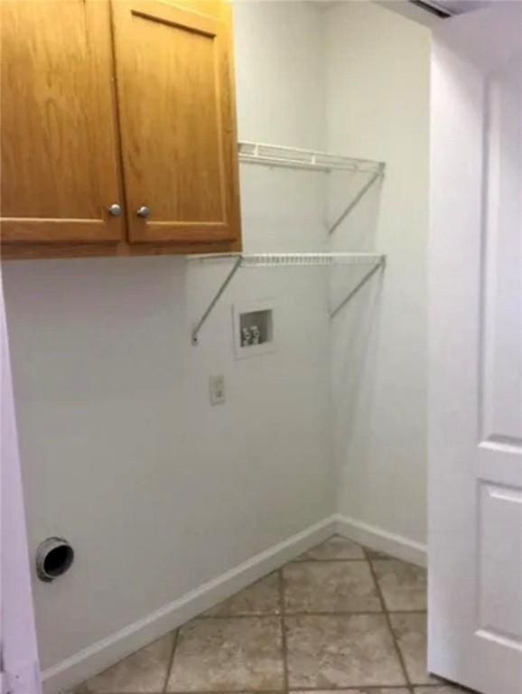 laundry room with hookup for a washing machine, light tile patterned floors, and cabinets