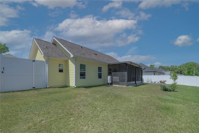 rear view of house featuring a yard, a fenced backyard, and a sunroom