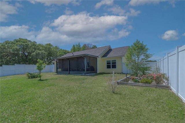 rear view of house with a yard, a garden, a fenced backyard, and a sunroom