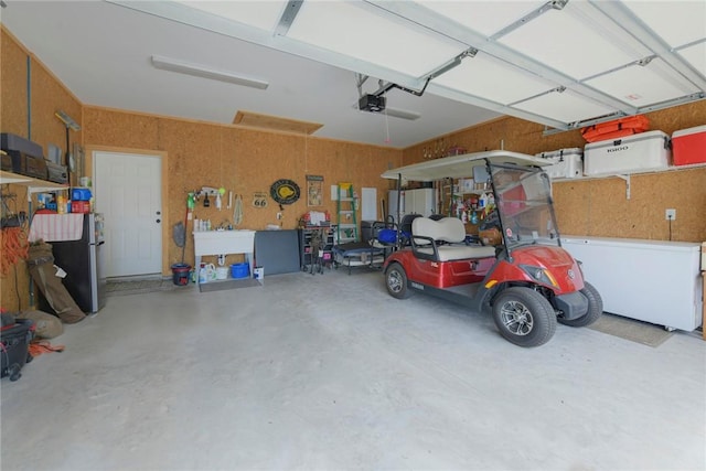 garage featuring freestanding refrigerator and a garage door opener