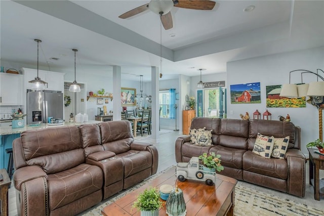 living area featuring a ceiling fan and a raised ceiling