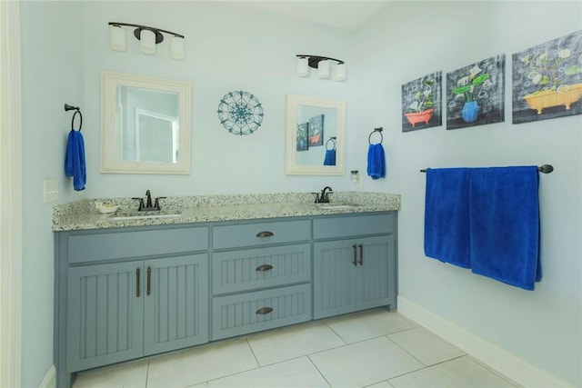 full bath featuring double vanity, tile patterned flooring, a sink, and baseboards