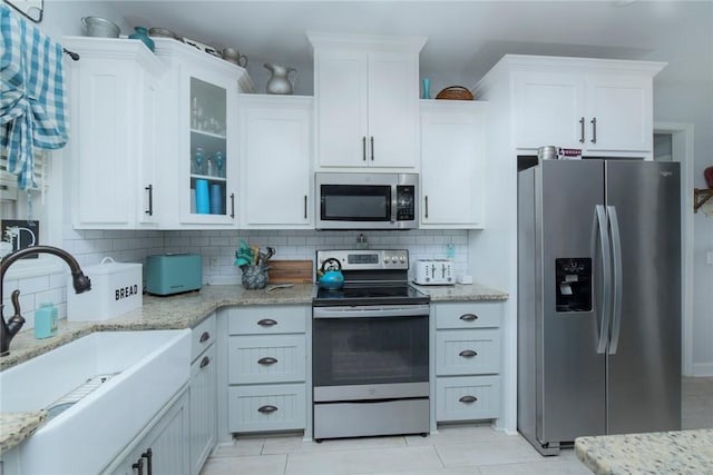 kitchen with stainless steel appliances, tasteful backsplash, a sink, and white cabinetry